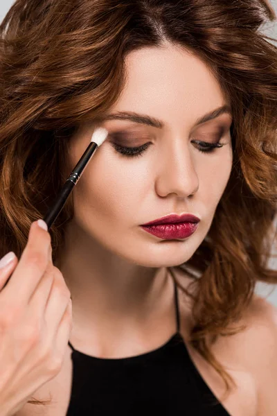 Cropped view of makeup artist apply eye shadow on beautiful woman isolated on grey — Stock Photo
