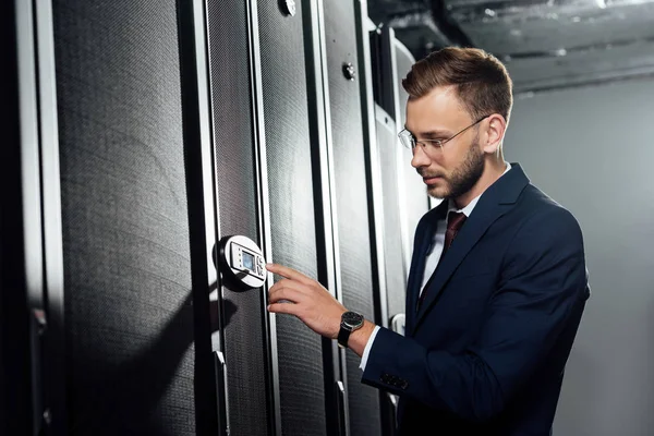 Selektiver Fokus eines gutaussehenden Geschäftsmannes in Anzug und Brille, der mit dem Finger auf ein digitales Panel zeigt — Stockfoto