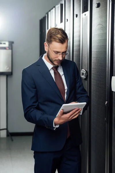 Hombre de negocios en traje usando tableta digital en el centro de datos - foto de stock