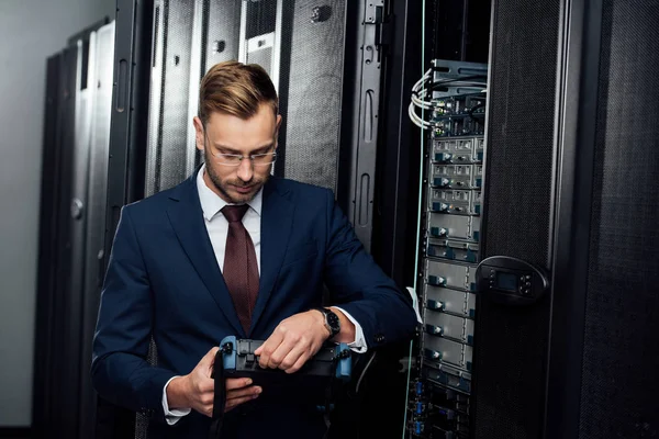 Бородатий бізнесмен тримає рефлектометр в кімнаті сервера — стокове фото