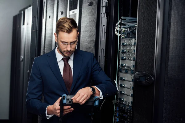 Hombre de negocios barbudo sosteniendo reflectómetro en la sala de servidores — Stock Photo