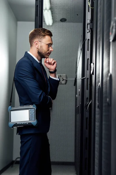 Вид збоку кропіткого бізнесмена, що стоїть з рефлектометром у серверній кімнаті — стокове фото