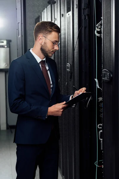 Bell'uomo d'affari in giacca e cravatta con appunti e penna nel data center — Foto stock