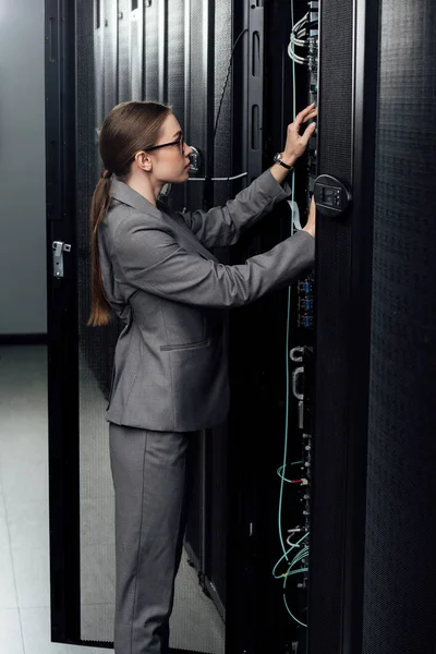 Attrayant femme d'affaires dans des lunettes regardant rack serveur dans le centre de données — Photo de stock