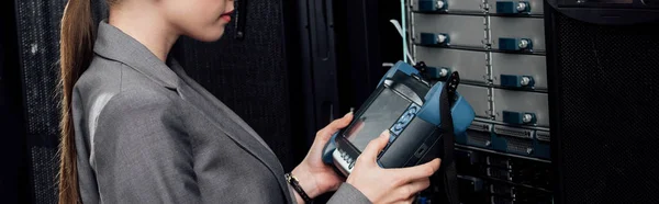 Panoramic shot of businesswoman holding reflectometer in data center — Stock Photo