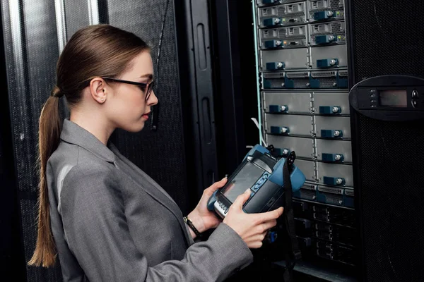 Side view of businesswoman holding reflectometer in data center — Stock Photo