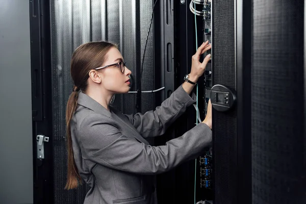 Empresária em óculos olhando para rack de servidor no data center — Fotografia de Stock