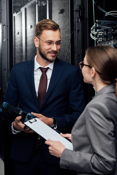 Selektiver Fokus eines gutaussehenden Geschäftsmannes mit Reflektometer in der Nähe einer Geschäftsfrau im Rechenzentrum — Stockfoto