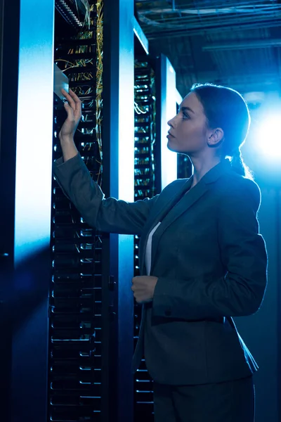 Attraente donna d'affari guardando rack server in data center — Foto stock