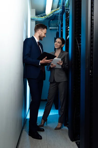 Cheerful businesswoman and businessman with clipboard in data center — Stock Photo