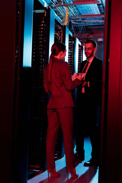 Businesswoman standing near server racks and bearded businessman in glasses — Stock Photo