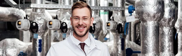 Panoramic shot of cheerful engineer in glasses and white coat — Stock Photo
