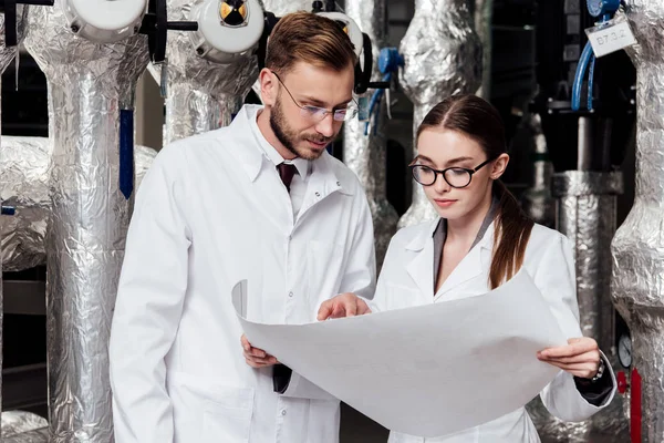Engineers in glasses looking at blueprint near air compressor system — Stock Photo