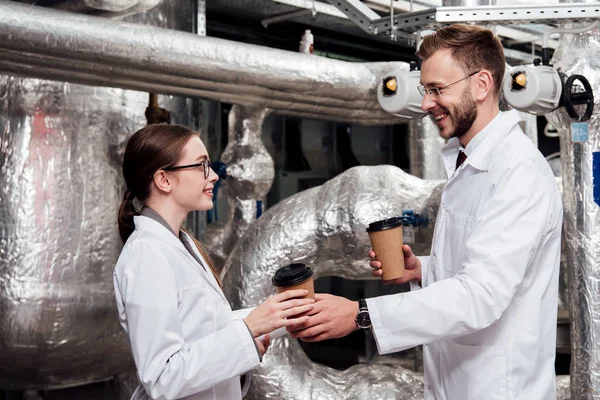 Fröhlicher Ingenieur mit Pappbechern in der Nähe glücklicher Mitarbeiter — Stockfoto