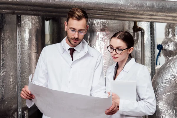 Engineers in white coats looking at blueprint — Stock Photo