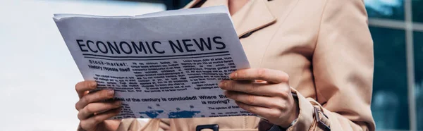 Tiro panorâmico de mulher em casaco de trincheira segurando jornal fora — Fotografia de Stock