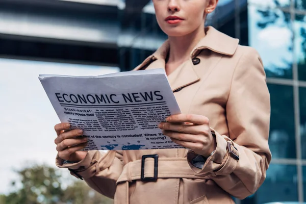 Cropped view of woman in trench coat holding newspaper outside — Stock Photo