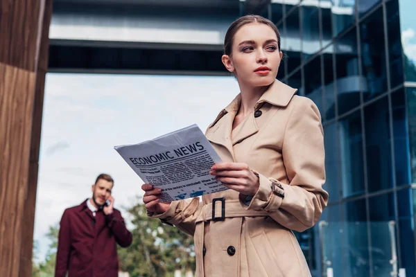Selective focus of beautiful woman holding newspaper near man — Stock Photo