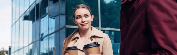 Plano panorámico de mujer atractiva mirando al hombre con café para ir - foto de stock