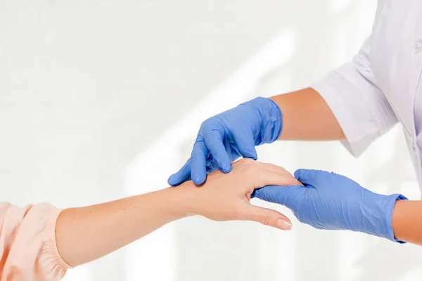 Vista recortada del dermatólogo examinando la piel del paciente con lupa en la clínica - foto de stock