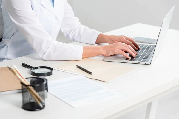 Ausgeschnittene Ansicht eines Ernährungswissenschaftlers, der am Tisch sitzt und Laptop in der Klinik benutzt — Stockfoto
