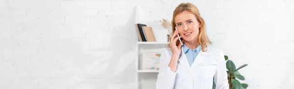 Plano panorámico de nutricionista atractivo hablando en teléfono inteligente en la clínica - foto de stock