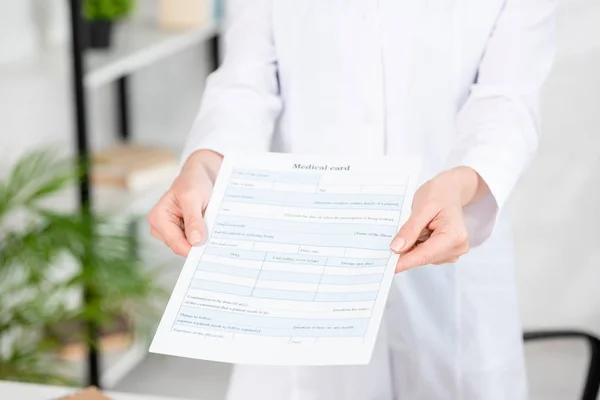 Visão cortada de nutricionista segurando cartão médico na clínica — Fotografia de Stock