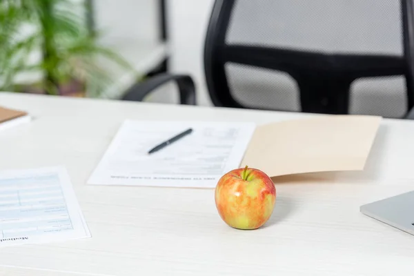 Enfoque selectivo de la manzana madura y entera en la mesa de madera en la clínica - foto de stock