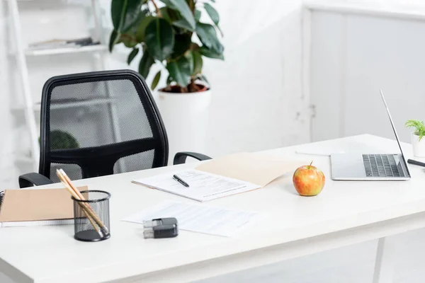 Pomme, papeterie, documents et ordinateur portable sur table en bois à la clinique — Photo de stock