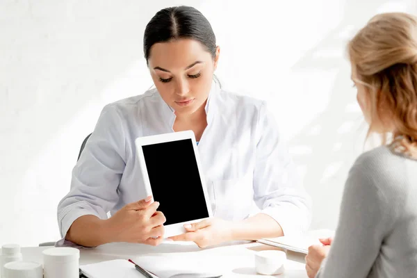 Dermatólogo mostrando tableta digital con espacio de copia al paciente en la clínica - foto de stock