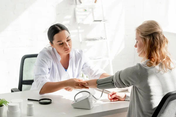 Attraktiver Hautarzt misst Blutdruck des Patienten in Klinik — Stockfoto