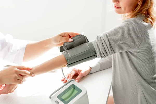 Vista ritagliata del dermatologo che misura la pressione sanguigna del paziente in clinica — Foto stock