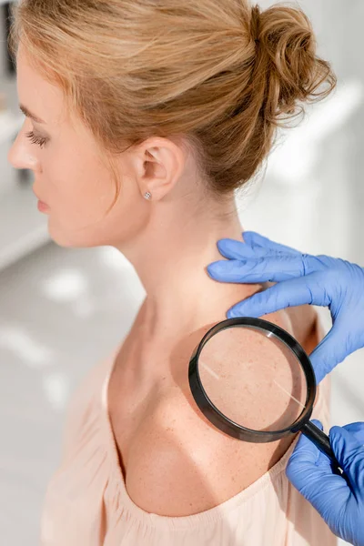 Ausgeschnittene Ansicht des Dermatologen bei der Untersuchung der Haut des Patienten mit der Lupe in der Klinik — Stockfoto