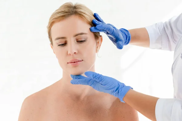 Ausgeschnittene Ansicht eines Dermatologen, der die Haut eines Patienten in der Klinik untersucht — Stockfoto