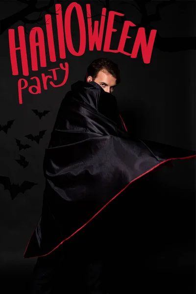 Man covering face with cloak on black background with Halloween party illustration — Stock Photo