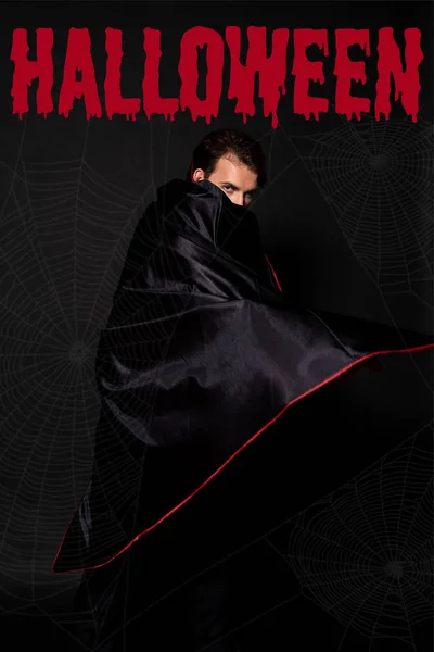 Hombre cubriendo la cara con capa sobre fondo negro con ilustración sangrienta de Halloween - foto de stock