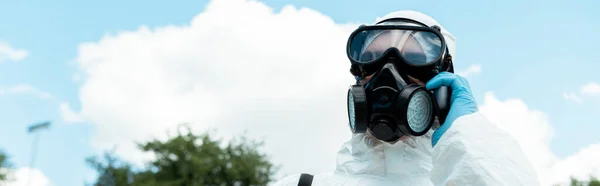 Spécialiste du nettoyage dans respirateur parler sur téléphone portable dans le parc pendant la pandémie de coronavirus, orientation panoramique — Photo de stock