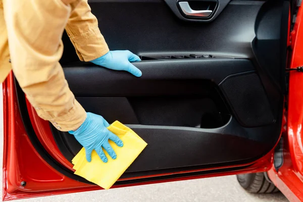 Обрезанный вид человека в латексных перчатках, моющего двери машины тряпкой во время пандемии ковида-19 — стоковое фото