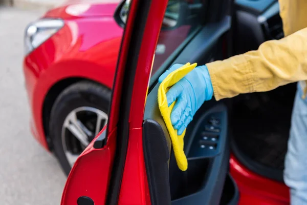 Partial view of man in medical glove cleaning car doors with rag during coronavirus pandemic — Stock Photo