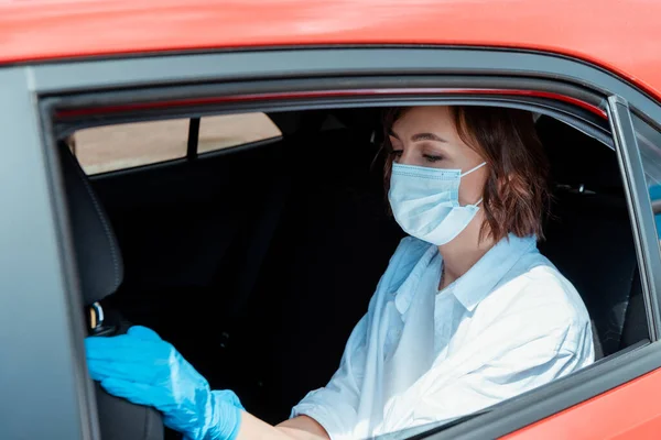 Girl in medical mask and gloves sitting in taxi during coronavirus pandemic — Stock Photo