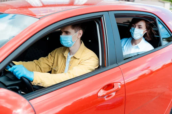 Male driver and woman in medical masks and gloves in taxi during covid-19 pandemic — Stock Photo