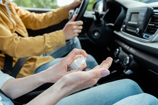 Обрезанный вид водителя такси и женщины, использующих антисептик в автомобиле во время пандемии ковид-19 — стоковое фото