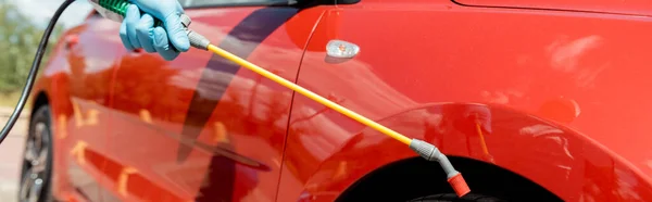 Visão cortada de especialista em carro de limpeza uniforme com desinfetante em saco de pulverização durante a pandemia covid-19, cultura horizontal — Fotografia de Stock