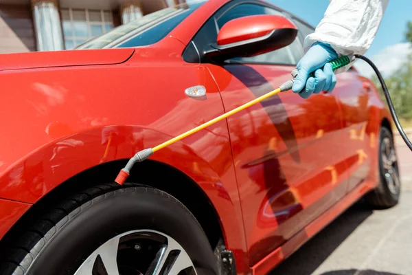 Обрізаний вид фахівця з очищення костюма автомобіля з дезінфікуючим спреєм під час пандемії ковадла-19 — стокове фото