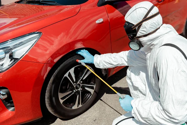 Specialista in hazmat suit e respiratore pulizia auto con disinfettante in sacchetto spray durante la pandemia coronavirus — Foto stock