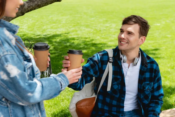 Messa a fuoco selettiva di ragazza felice dando tazza di carta con caffè per bello amico — Foto stock