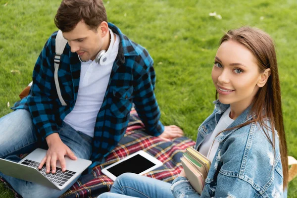 Messa a fuoco selettiva di attraente ragazza sorridente vicino studente utilizzando laptop, concetto di studio online — Foto stock