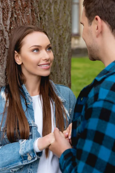 Messa a fuoco selettiva di giovane studente e attraente ragazza guardando l'un l'altro mentre si tiene per mano — Foto stock