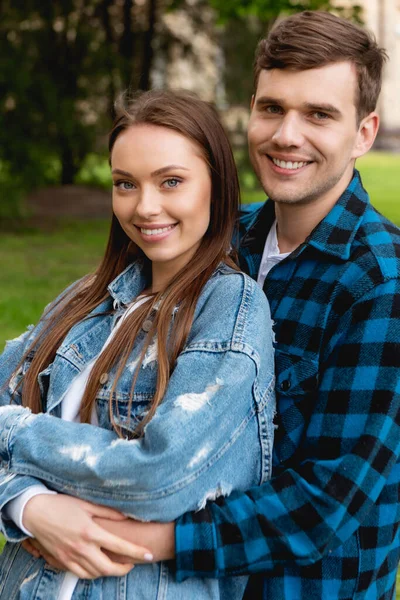 Cheerful student hugging attractive girlfriend in denim jacket — Stock Photo