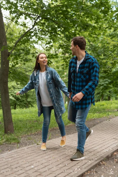 Couple joyeux tenant la main et se regardant dans le parc — Photo de stock